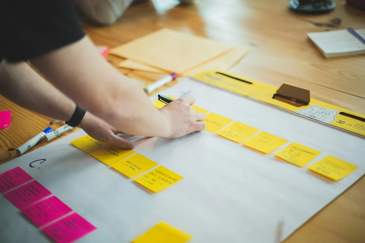 A course designer laying out an eLearning storyboard with sticky notes on a large sheet of paper