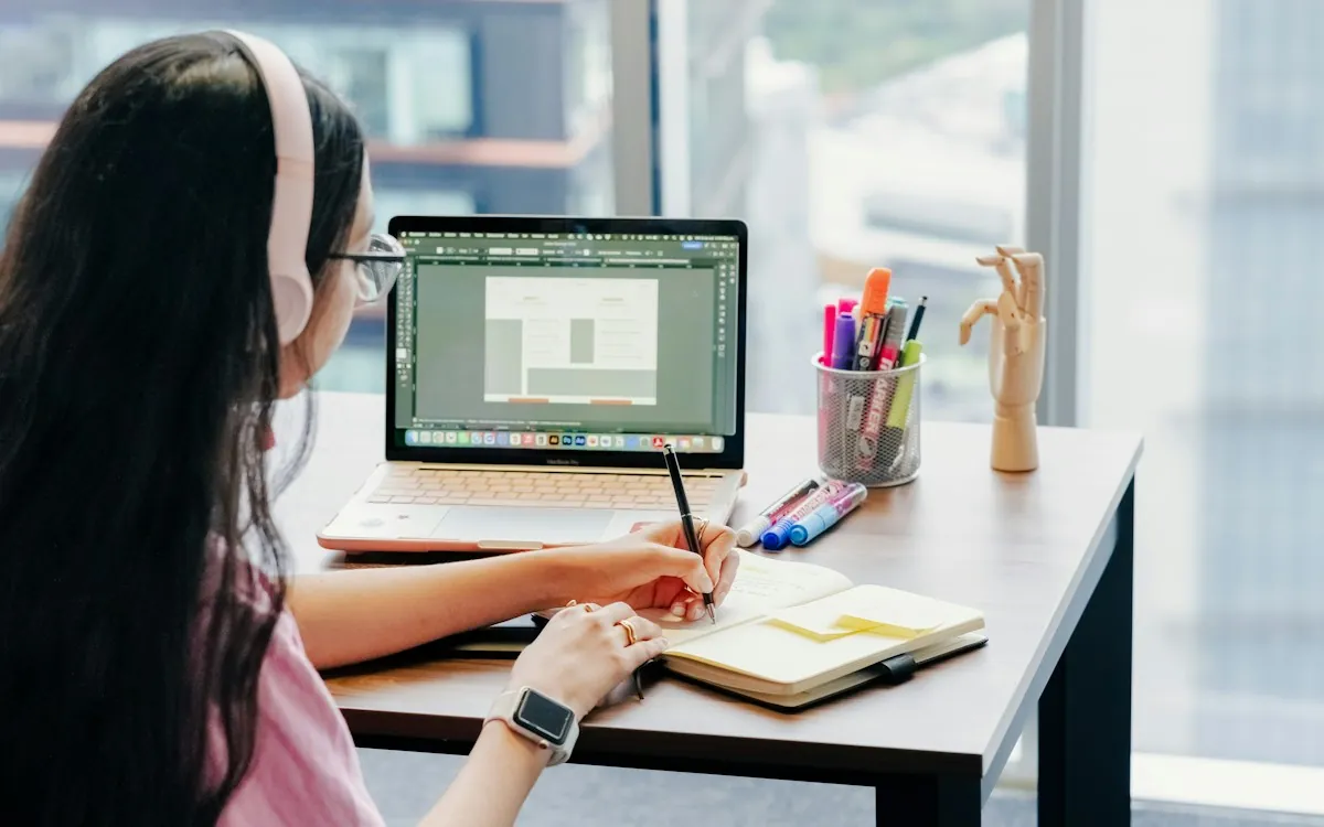 eLearning designer sketching a custom course layout beside her laptop