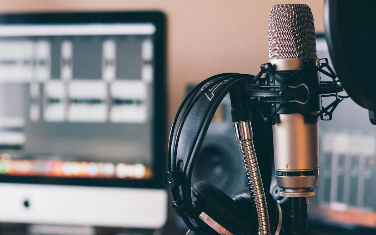 A studio microphone and headphones in front of audio editing software, ready to record eLearning voiceover