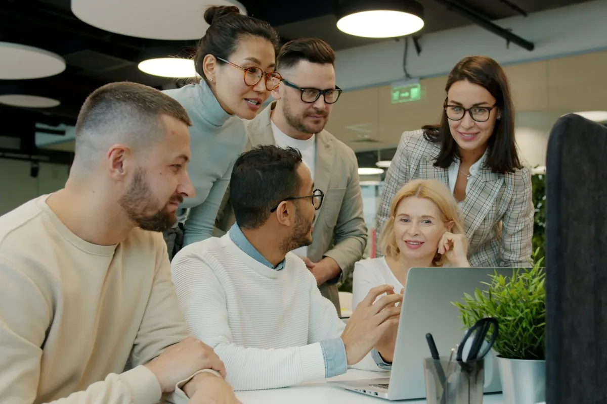 An L&D team gathered around a desk reviewing a new learning platform on a computer screen