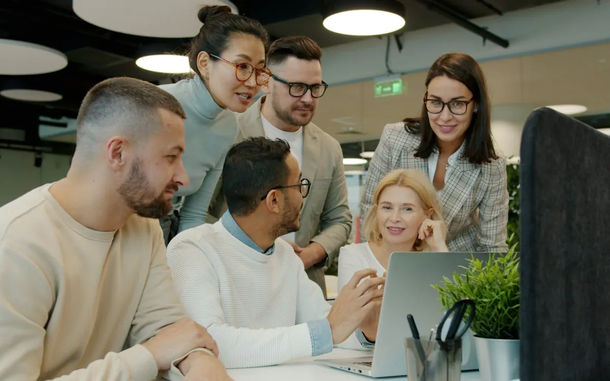 An L&D team gathered around a laptop planning what a course should track
