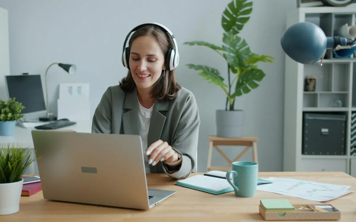 Translator with headphones reviewing a localized course on a laptop